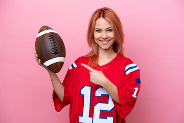 Young Russian girl playing rugby isolated on pink background and pointing it