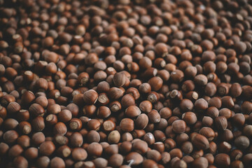 Hazelnuts in a wooden bowl on rustic background, Hazelnut background with green leaf