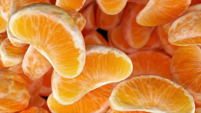 Close-up of juicy, vibrant orange tangerine segments stacked together, showcasing their fresh texture and bright color.

