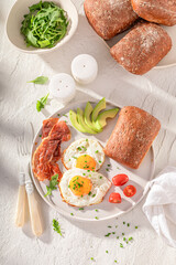 British breakfast with egg, tomato and rolls.