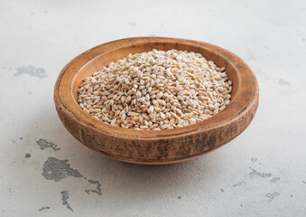Wooden bowl of dry raw organic oats seeds on light table.Macro.