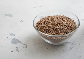 Raw dry white lentils seeds in glass bowl on light table.Macro.