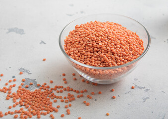 Dry raw orange lentils seeds in glass bowl on light table.Macro.