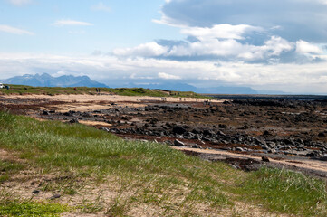 Ytri Tunga Iceland, basalt rocks in bay with people hiking in background