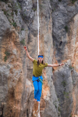 A tightrope walker walks along a cable stretched over a canyon.
