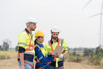 Male and female engineer at windmill field farm, wearing safety uniform and working and inspecting quality of wind turbines