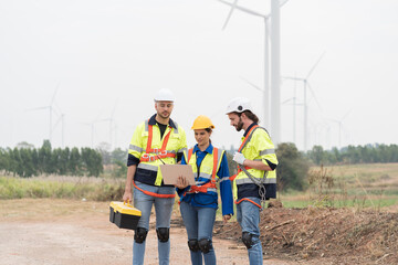 Male and female engineer at windmill field farm, wearing safety uniform and working and inspecting quality of wind turbines