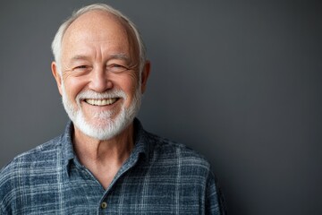 Obraz premium Smiling elderly man with white beard against gray background