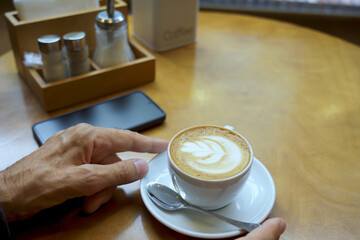 Human's hand holding coffee cup on table.
