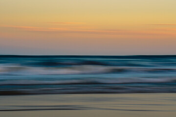 Fototapeta premium Gentle waves and pastel skies create a peaceful, abstract seascape.