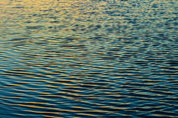 Golden light reflects on rippling water at sunset.
