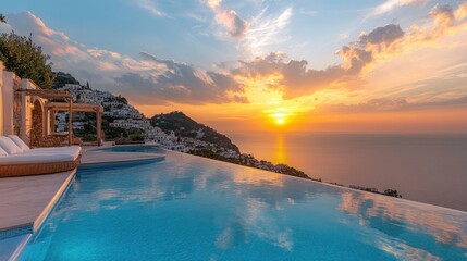 Fototapeta premium A luxury resort pool with Mediterranean Sea views and a sunset sky, with a hillside town in the backdrop.