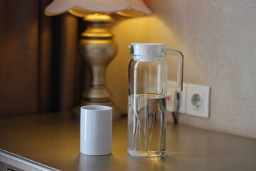 Bottle of water with glass on desk in light office, closeup