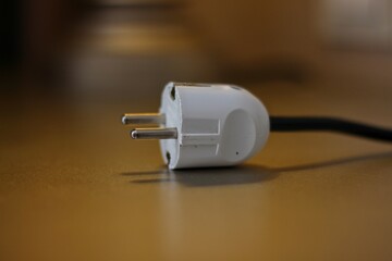 Electric plug on table. Electric plug isolated on blurred background. Black White power cable with plug. Power cord close-up