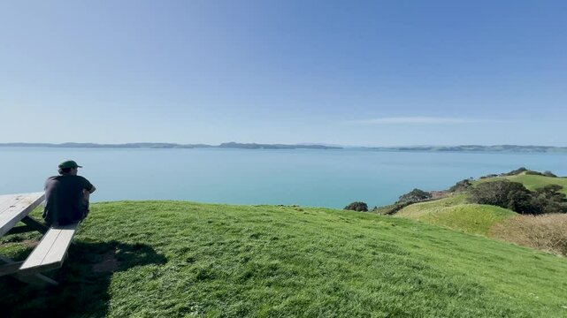 View of a park in New Zealand. Blue ocean and green grass field on spring day. Duder Park.