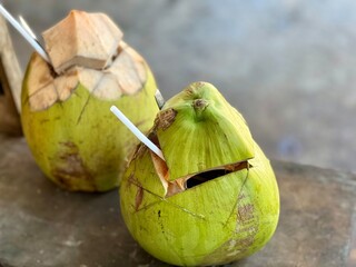 Tropical summer drink, two green fresh coconut drink on the wooden chair ready to deliver to...