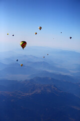 balloons in the sky over mountains