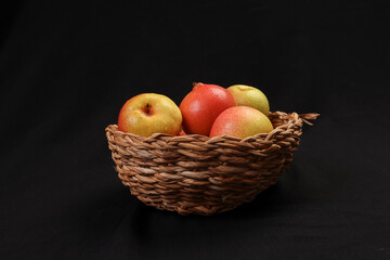 Green yellow red ripe mini pear sweet juicy in basket on wooden table dark background