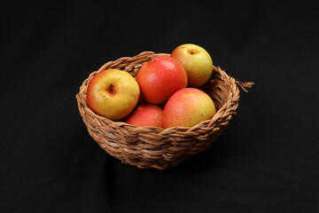 Green yellow red ripe mini pear sweet juicy in basket on wooden table dark background