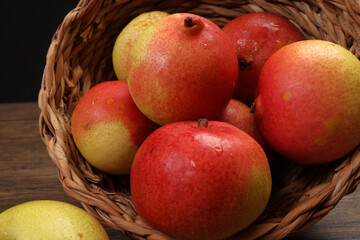 Green yellow red ripe mini pear sweet juicy in basket on wooden table dark background