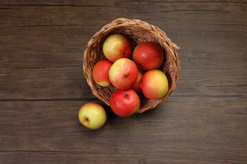 Green yellow red ripe mini pear sweet juicy in basket on wooden table dark background