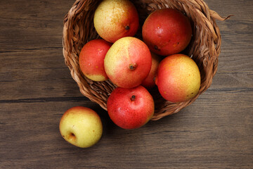 Green yellow red ripe mini pear sweet juicy in basket on wooden table dark background