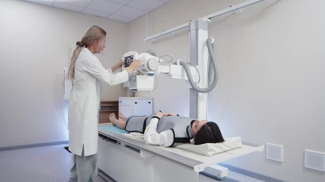 A specialist doctor in an X-ray room, a radiologist sets up a machine for radiography of a patient and makes a scan. The concept of medical technologies, modern medical equipment.