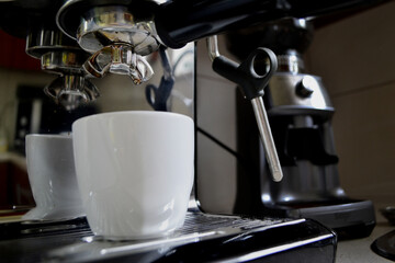 Making the perfect morning espresso. A coffee machine pours freshly brewed hot coffee into a white cup. High quality photo