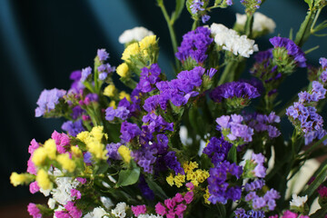 Bouquet of multicolored flowers in a vase (Limonium sinuatum, Statice sinuata) on a green background