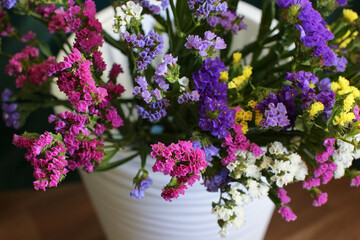 Bouquet of multicolored flowers in a vase (Limonium sinuatum, Statice sinuata) on a green background