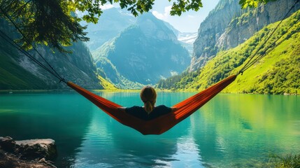 Woman relaxes in hammock overlooking a serene mountain lake.