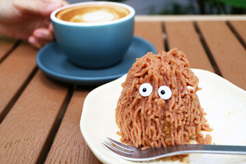 Delectable Monster Shaped Mont Blanc Cake with Blurry Hot Coffee in the Backdrop