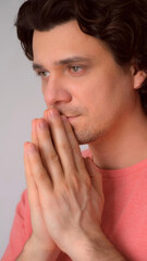 Portrait of pleading curly brunet middle aged man folded hands in prayer pose. Guy thinking dreaming worrying about future life feeling anxiety nervousness. Praying begging good things. Pray, prayer.