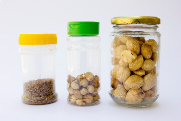 Three types of cooking spices each in a jar. There are candlenut seeds, cardamom seeds and cumin seeds.