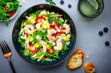 Shrimp salad with strawberries, onions, lettuce and almonds, gray background, top view