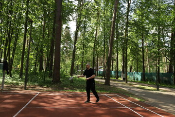 Badminton player, man competing in a match outside, popular sport with a shuttlecock