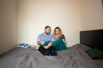 Family relaxing at home, husband and wife looking at phone screen, sharing a happy moment, enjoying their media together, relaxing in cosy comfort.