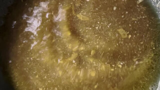 The water in the pot is a yellowish-brown color, with white stains on the surface and small bubbles floating at the bottom. The camera angle shows an overhead view of the water's surface. 