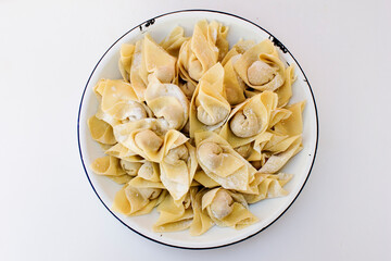 To make pangsit, you typically combine flour, corn flour, and water, then knead the dough until it is smooth and elastic. The filling, such as minced meat, shrimp, garlic, and parsley, is placed in th