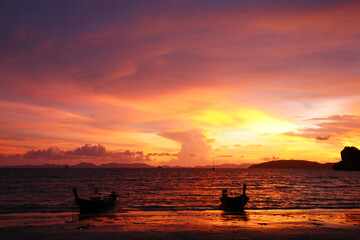 Unbelievable orange and purple sunset over the sea with two boats, Thailand