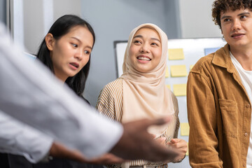 Diverse business team discussing project ideas during a meeting, including middle eastern, asian, and caucasian team members working together in a modern corporate office environment, teamwork concept