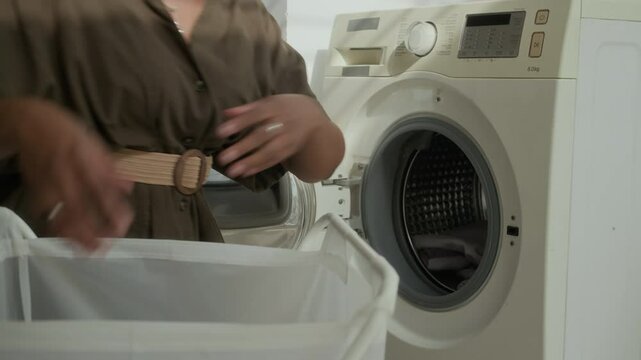 Cropped shot of young housewife filling washing machine with dirty laundry at home