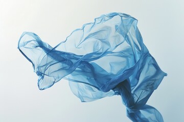 Fototapeta premium A faded blue plastic bag, its logo barely visible, carried by the wind against a flawless white canvas