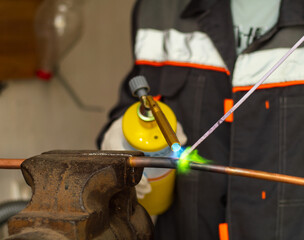 worker soldering copper pipes with a gas torch