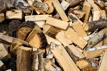 Stack of birch firewood with hand chopping block. Chopped firewood for winter. Lot of firewood - harvesting wood for heating the house. Horizontal photo. Chopped firewood background and texture.