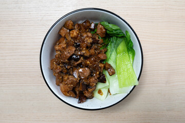 A bowl of rice topped with pork sauce and bok choy.