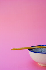A white and blue ceramic bowl and a wooden chopstick on top of the bowl.