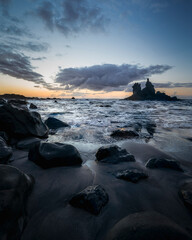 Tenerife, June 2022: A rock strewn bay at sunset with the tide rolling in