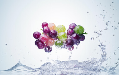 A cluster of colorful grapes, including red, green, and purple varieties, splashes into a pool of water.