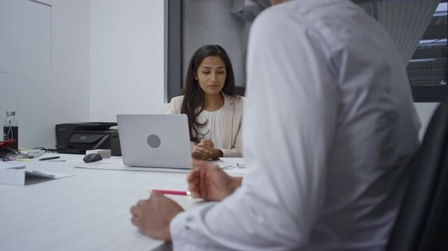 Young Indian woman, a hiring manager, having an intake meeting with an HR recruiting team member about job qualifications, handheld shot. Office theme concept.